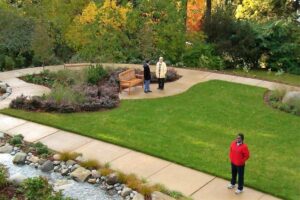 Three people standing on the paths that wind through the well-maintained and verdant grounds of the Peace and Spirituality Center at St. Mary's.