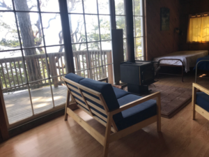 bedroom with twin bed, couches and wood stove at indralaya mindfulness retreat