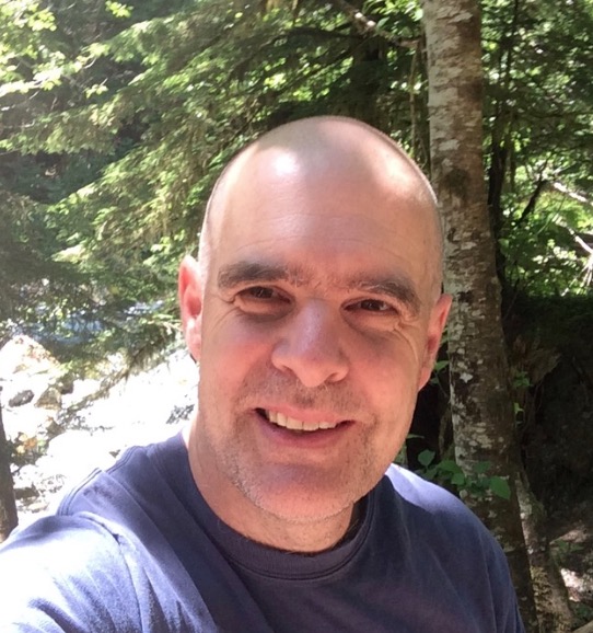 Tim Burnett Hiking Selfie A selfie of Tim Burnett, smiling on a hiking trip in the Cascade Mountains of Washington.
