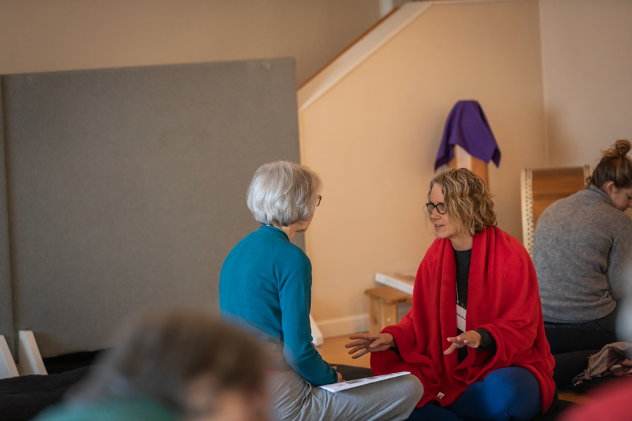mindful-inquiry-discussion-mindfulness-meditation-classes-wa-seattle-bellingham Two mindfulness students sitting on the ground inside the dharma hall, deep in discussion about their experience with a meditation.