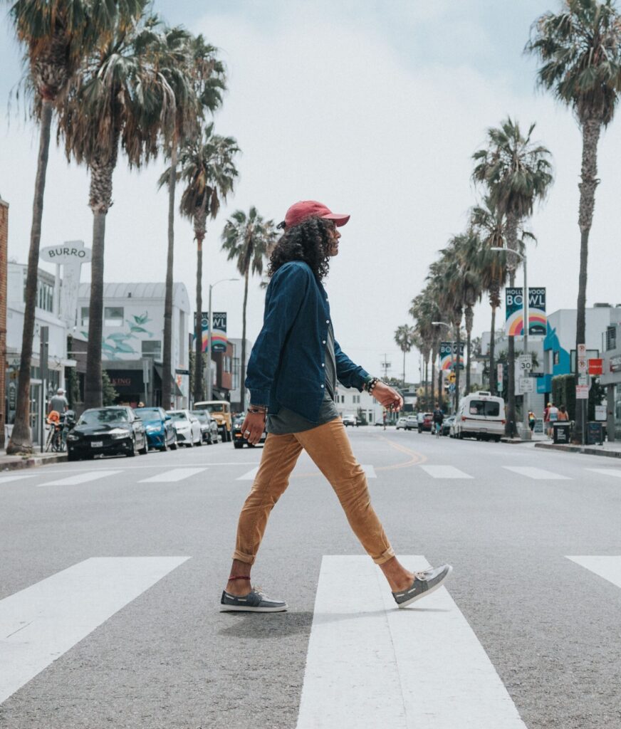 Person walking across palm treed street