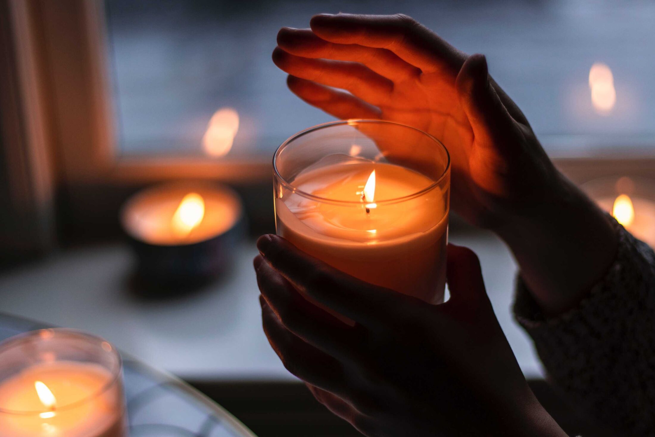 hand-cancels-warm-holding A hand hovers near a lit candle